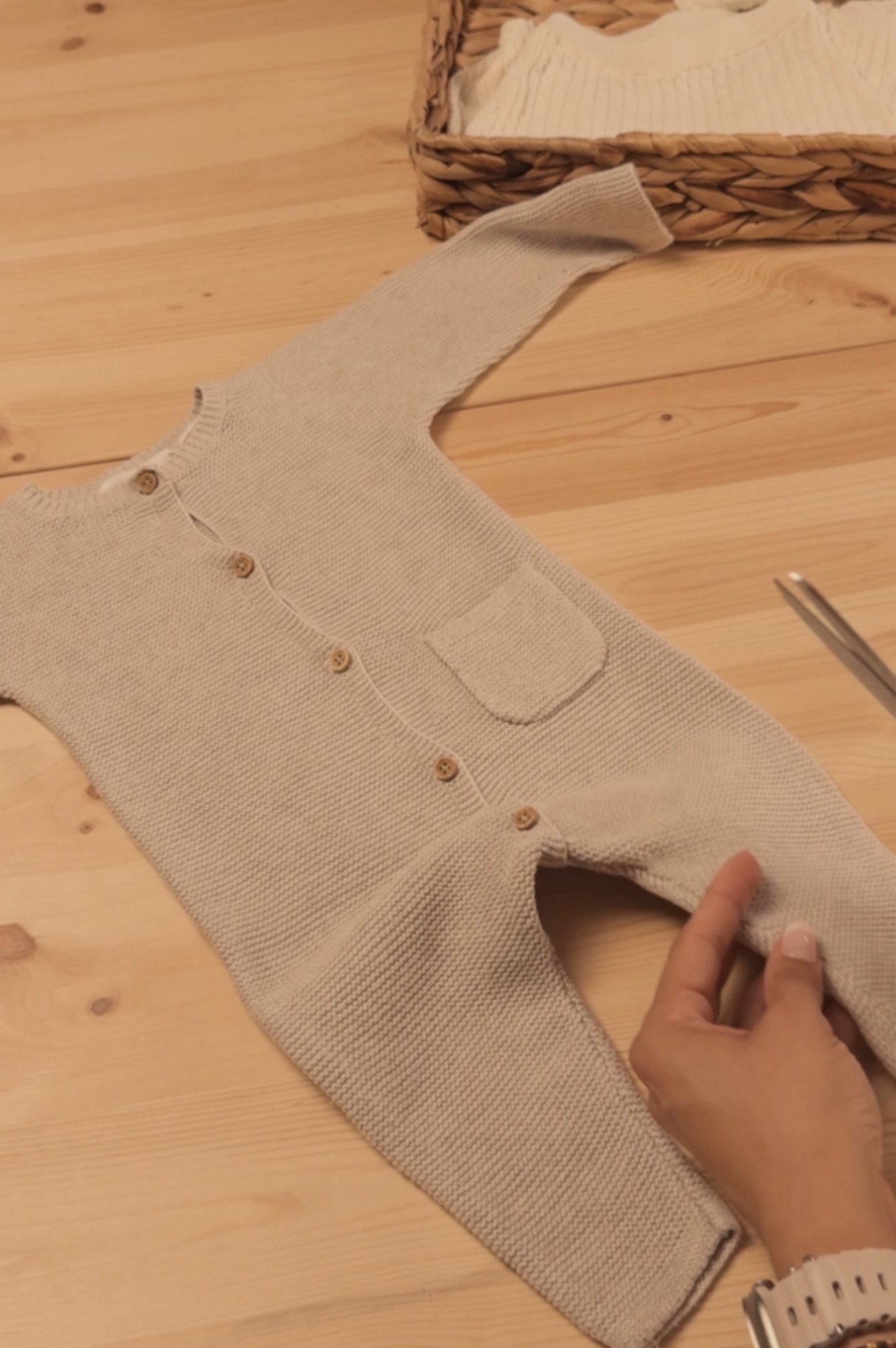 Pelele de punto de bebé extendido sobre la mesa del taller, antes de convertirse en oso